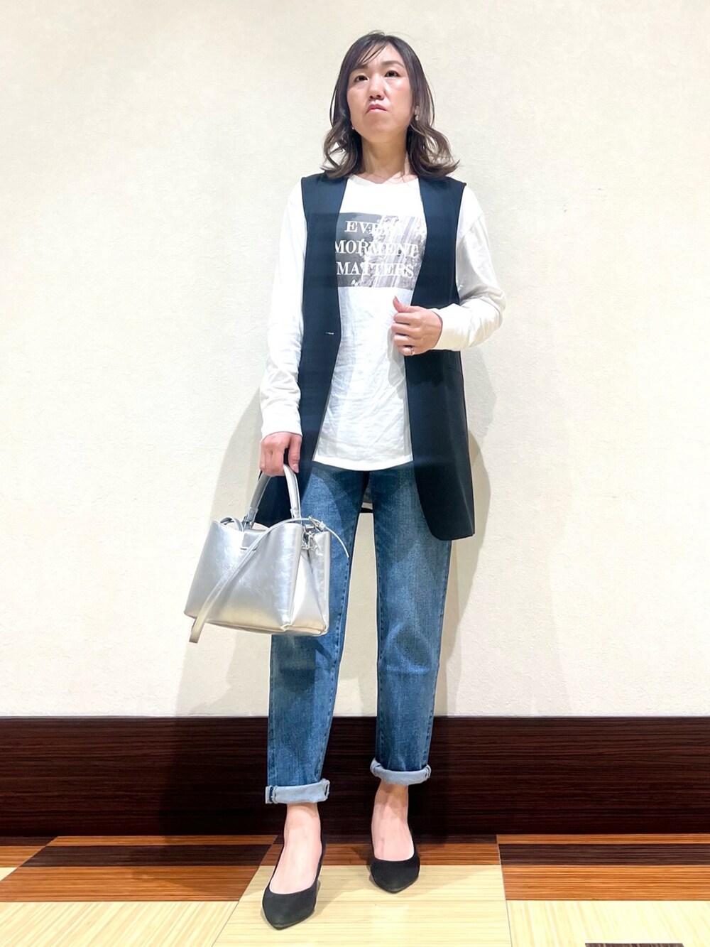 ホワイト系のTシャツ/カットソー、ブラック系のベスト、ブルー系のデニムパンツを着用したレディースの春コーディネートの2枚目の写真