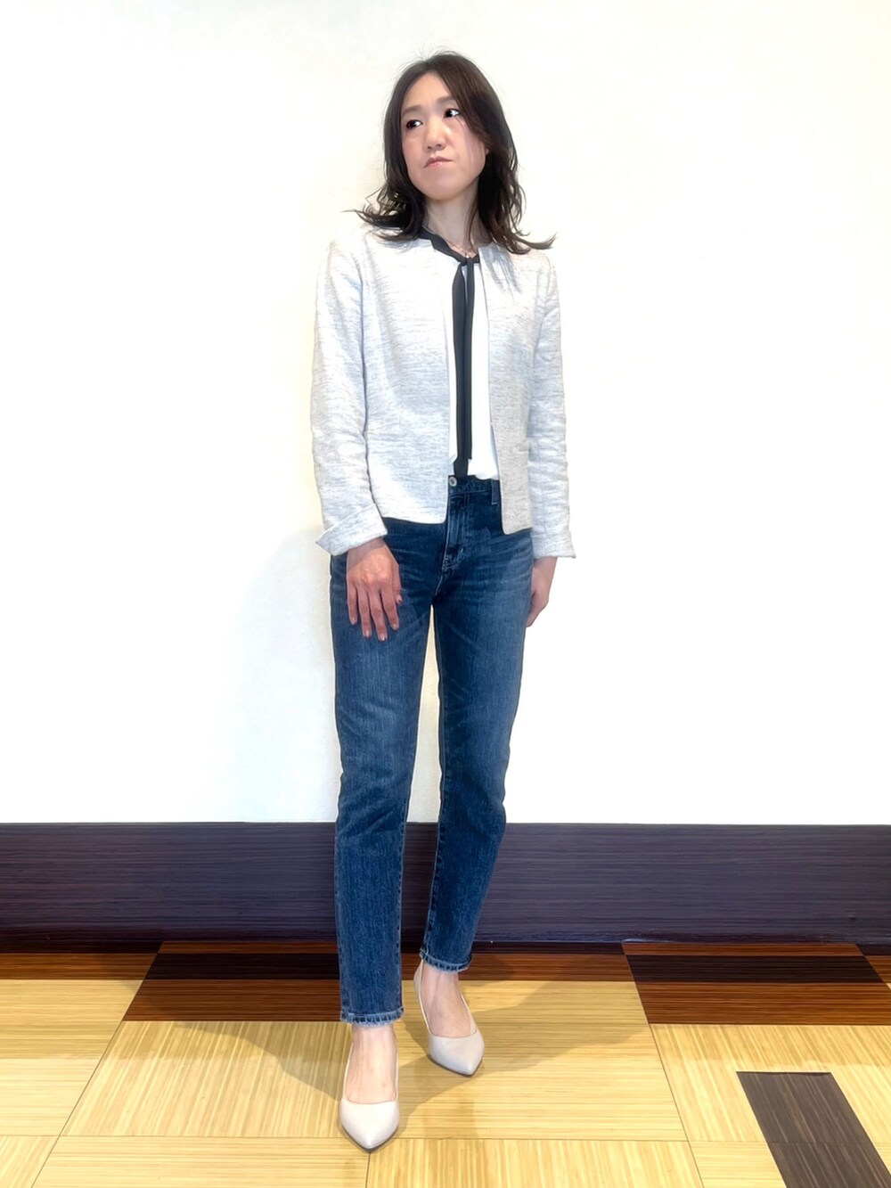 ブラック系のノーカラージャケット、ホワイト系のシャツ/ブラウス、ブルー系のデニムパンツを着用したレディースの春コーディネートの2枚目の写真