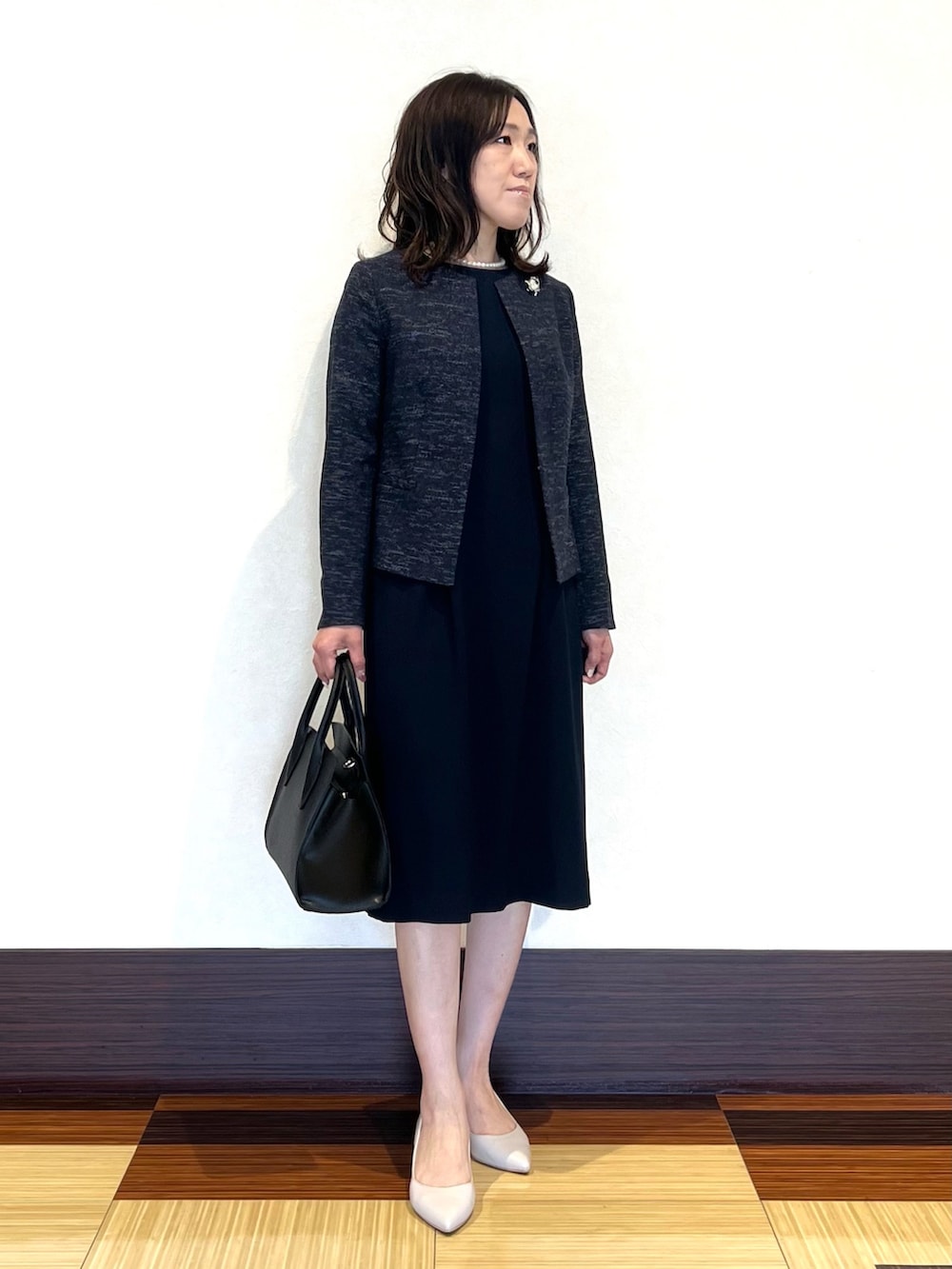 ブラック系のノーカラージャケット、ブラック系のワンピース、ブラック系のショルダーバッグを着用したレディースの冬コーディネートの3枚目の写真