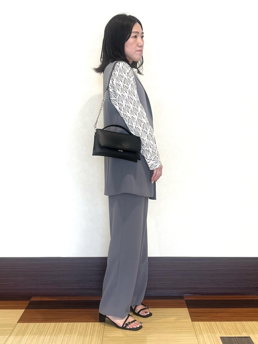 グレー系のベスト、ホワイト系のシャツ/ブラウス、グレー系のスーツパンツを着用したレディースの秋コーディネートの4枚目の写真