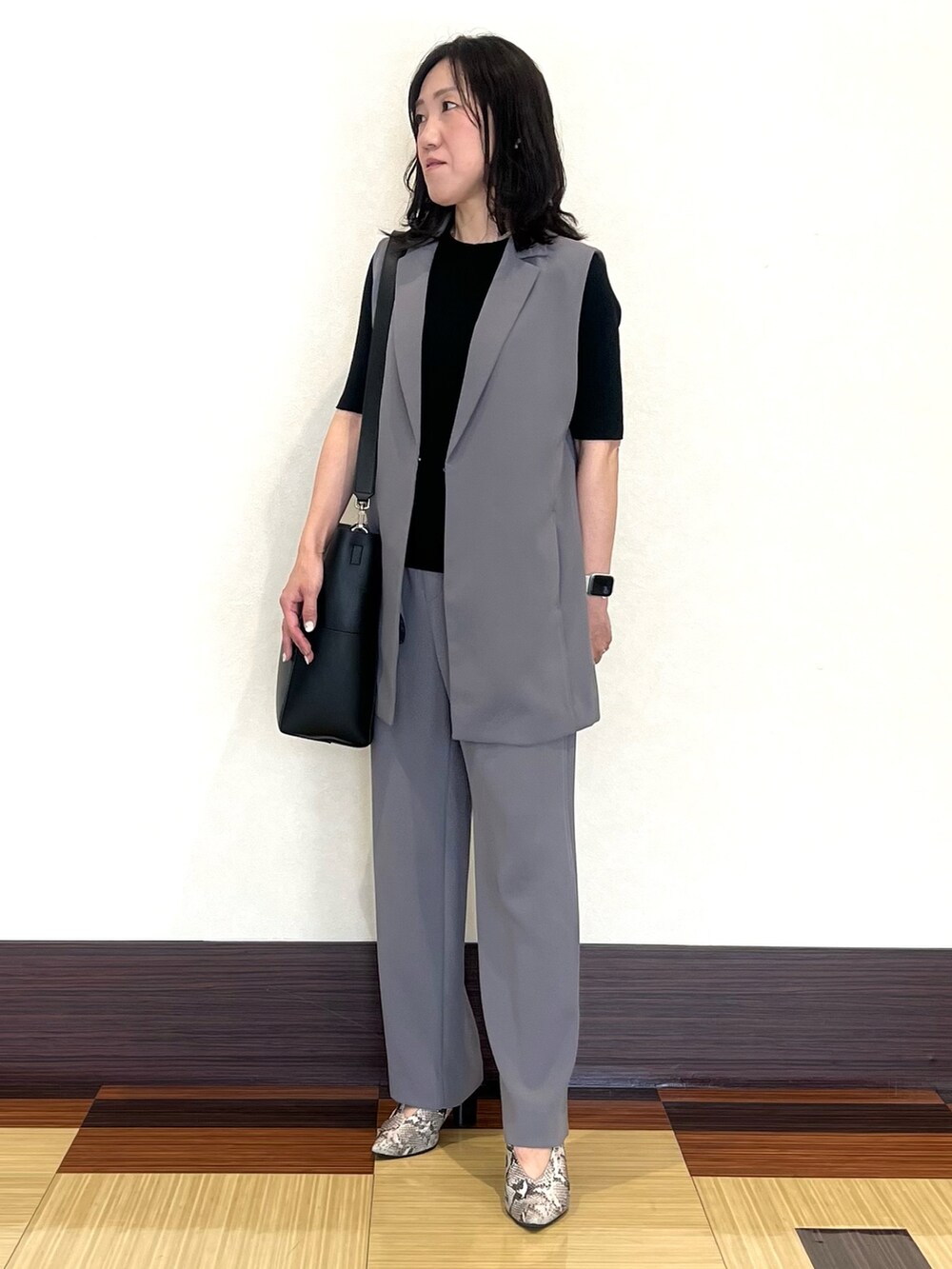 ブラック系のニット/セーター、グレー系のベスト、グレー系のスーツパンツを着用したレディースの秋コーディネートの4枚目の写真