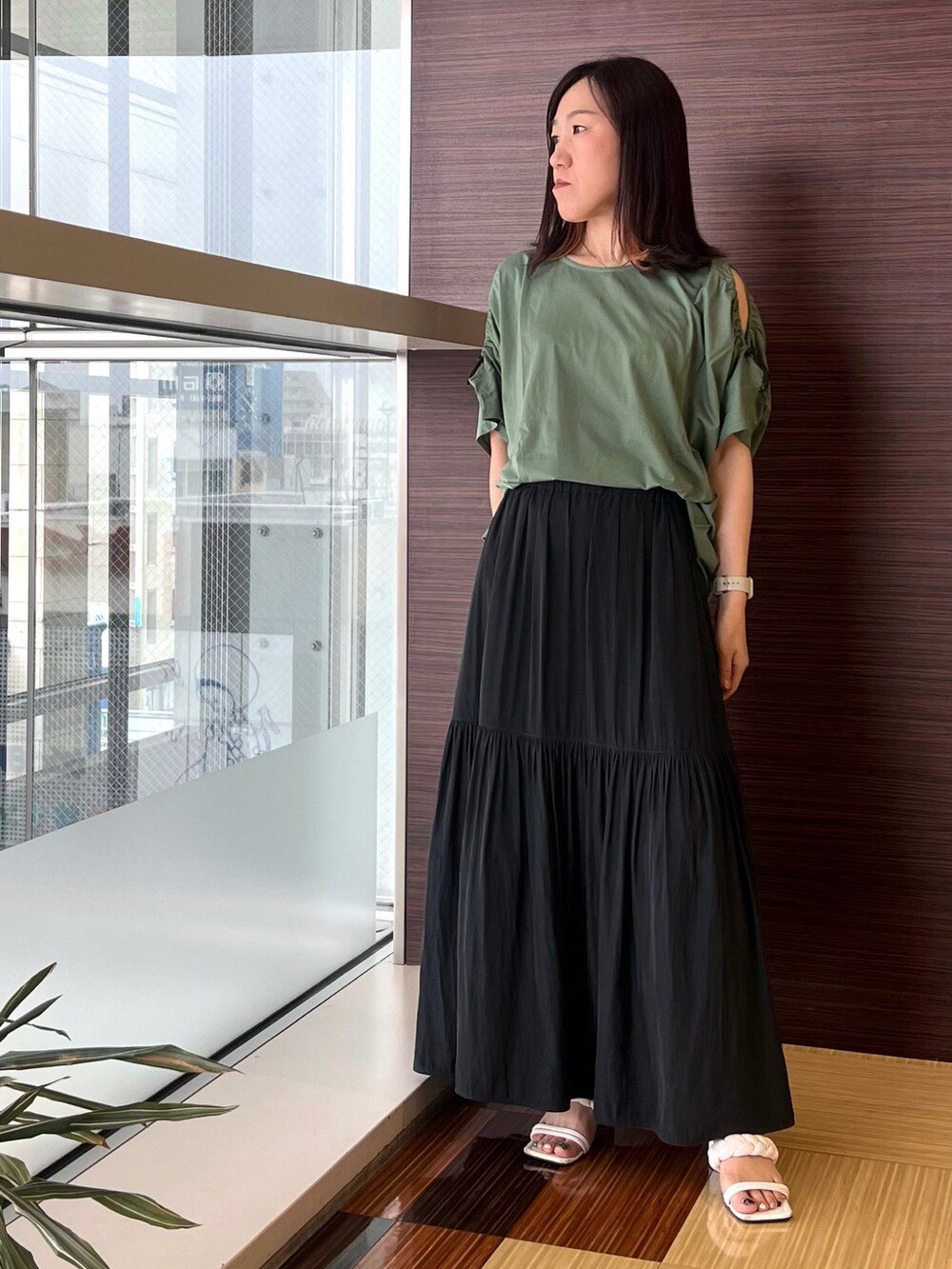 グリーン系のTシャツ/カットソー、グレー系のスカート、ホワイト系のサンダルを着用したレディースの夏コーディネートの2枚目の写真