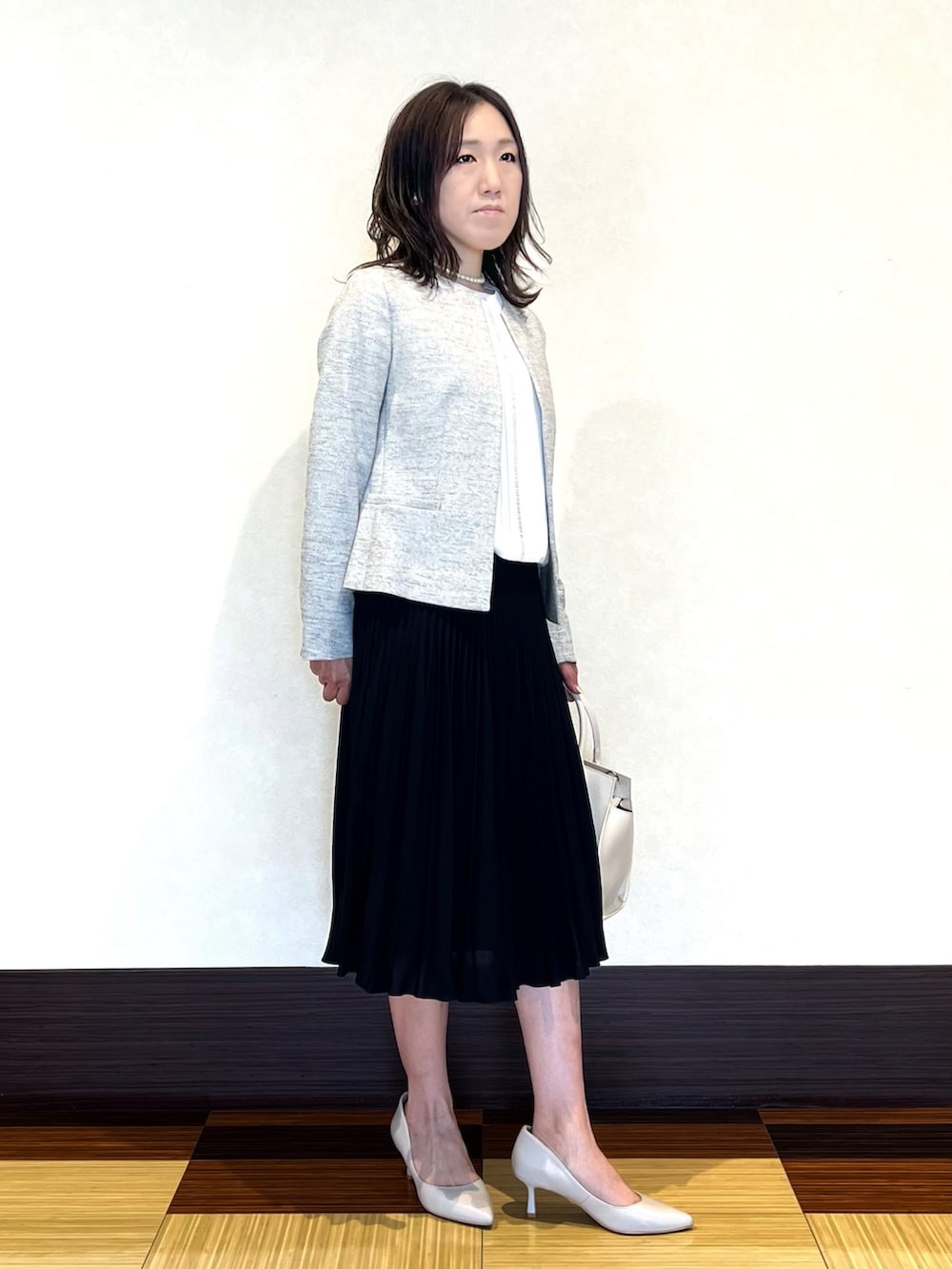 ホワイト系のシャツ/ブラウス、ブラック系のノーカラージャケット、ブルー系のスカートを着用したレディースの冬コーディネートの2枚目の写真