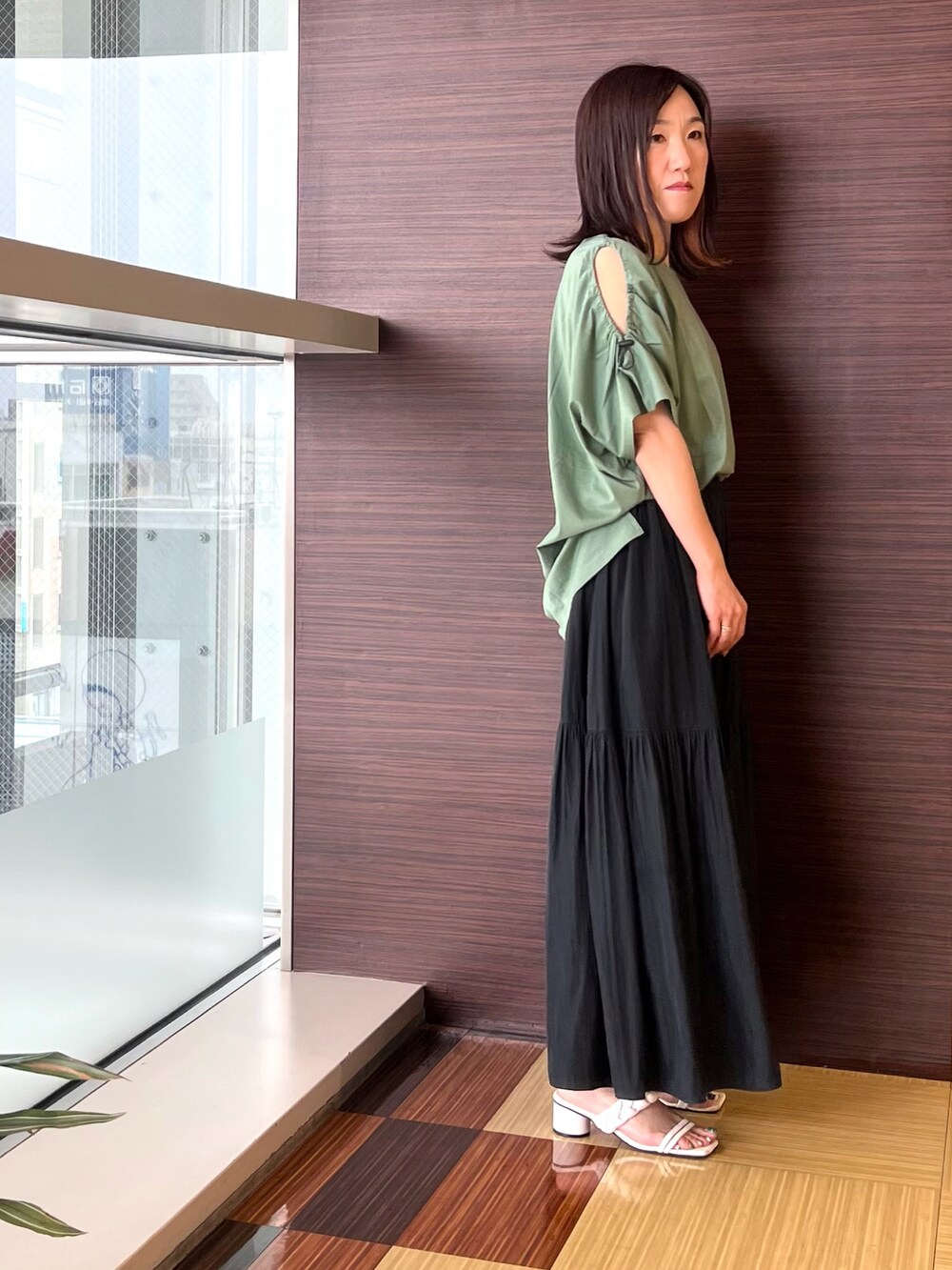 グリーン系のTシャツ/カットソー、グレー系のスカート、ホワイト系のサンダルを着用したレディースの夏コーディネートの3枚目の写真