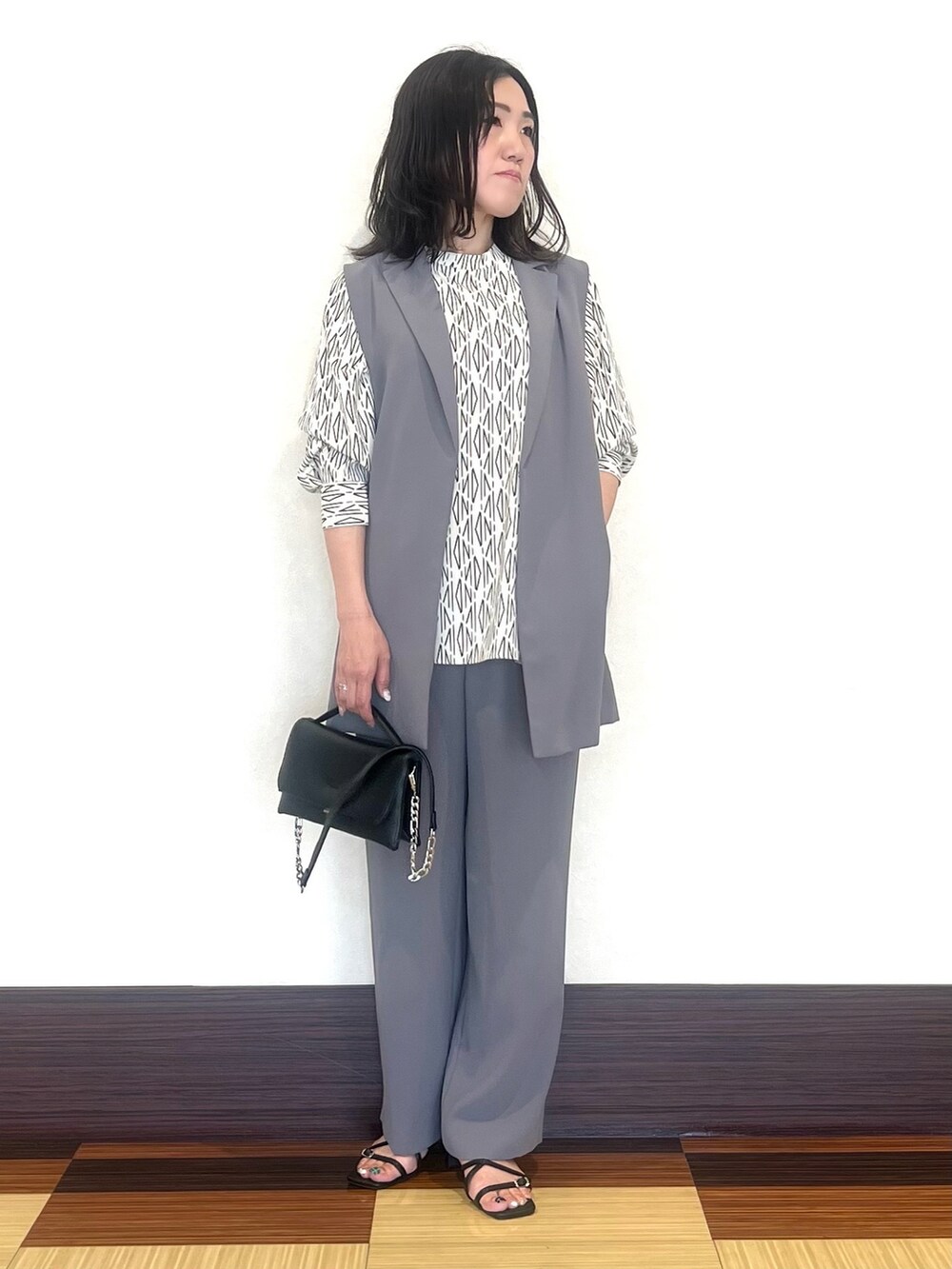 グレー系のベスト、ホワイト系のシャツ/ブラウス、グレー系のスーツパンツを着用したレディースの秋コーディネートの2枚目の写真