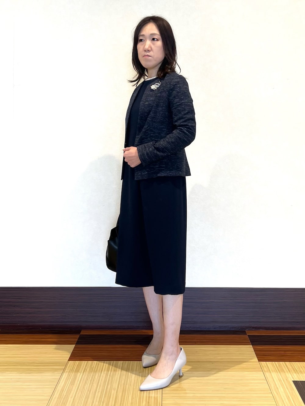 ブラック系のノーカラージャケット、ブラック系のワンピース、ブラック系のショルダーバッグを着用したレディースの冬コーディネートの4枚目の写真