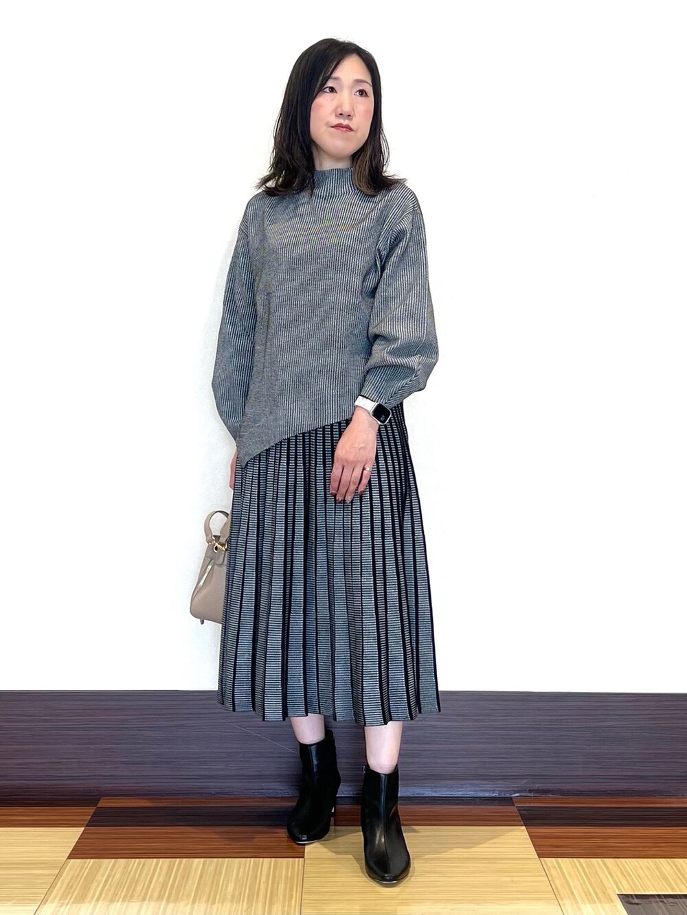 ブラック系のニット/セーター、ブラック系のスカート、ブラック系のブーツを着用したレディースの秋コーディネートの2枚目の写真