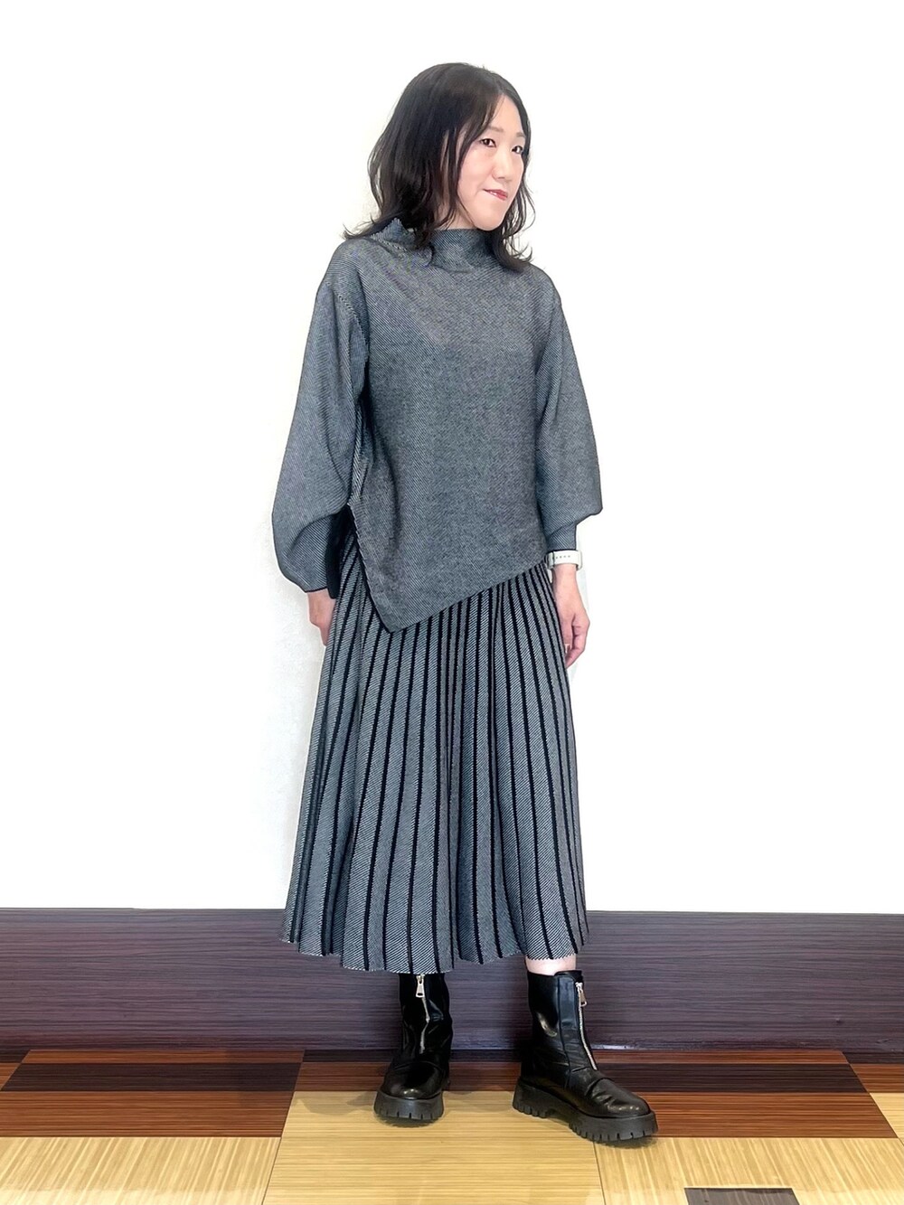 ブラック系のニット/セーター、ブラック系のスカート、ブラック系のブーツを着用したレディースの秋コーディネートの2枚目の写真