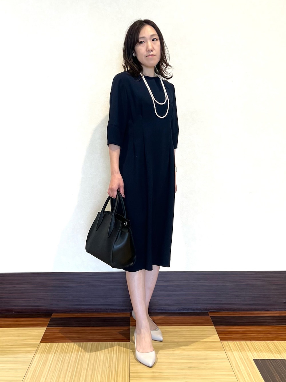 ブラック系のノーカラージャケット、ブラック系のワンピース、ブラック系のショルダーバッグを着用したレディースの冬コーディネートの5枚目の写真