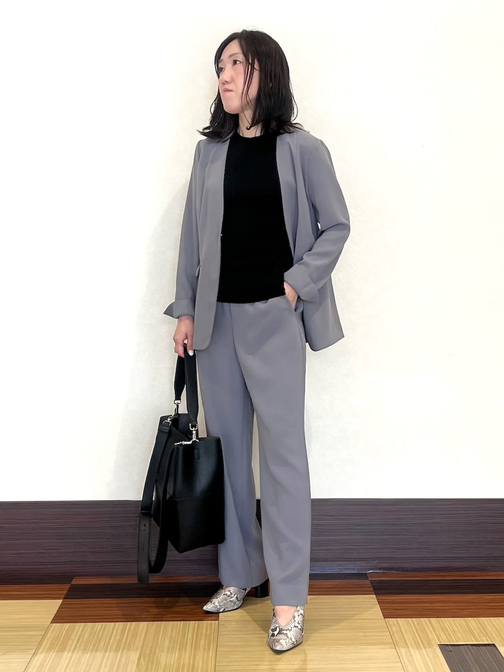 ブラック系のニット/セーター、グレー系のスーツジャケット、グレー系のスーツパンツを着用したレディースの秋コーディネートの3枚目の写真