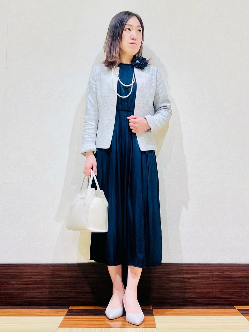 ホワイト系のスーツジャケット、ブルー系のワンピース、ホワイト系のハンドバッグを着用したレディースの冬コーディネートの2枚目の写真