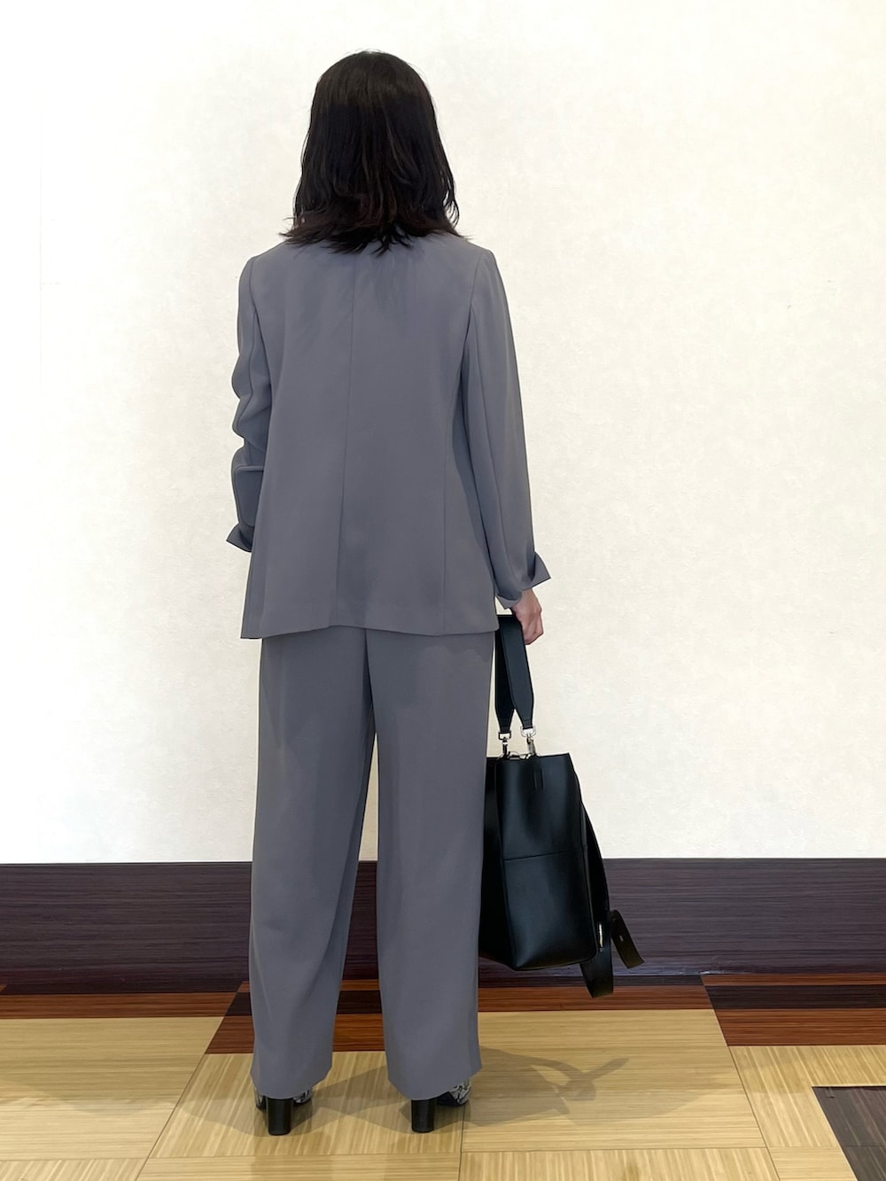 ブラック系のニット/セーター、グレー系のスーツジャケット、グレー系のスーツパンツを着用したレディースの秋コーディネートの5枚目の写真
