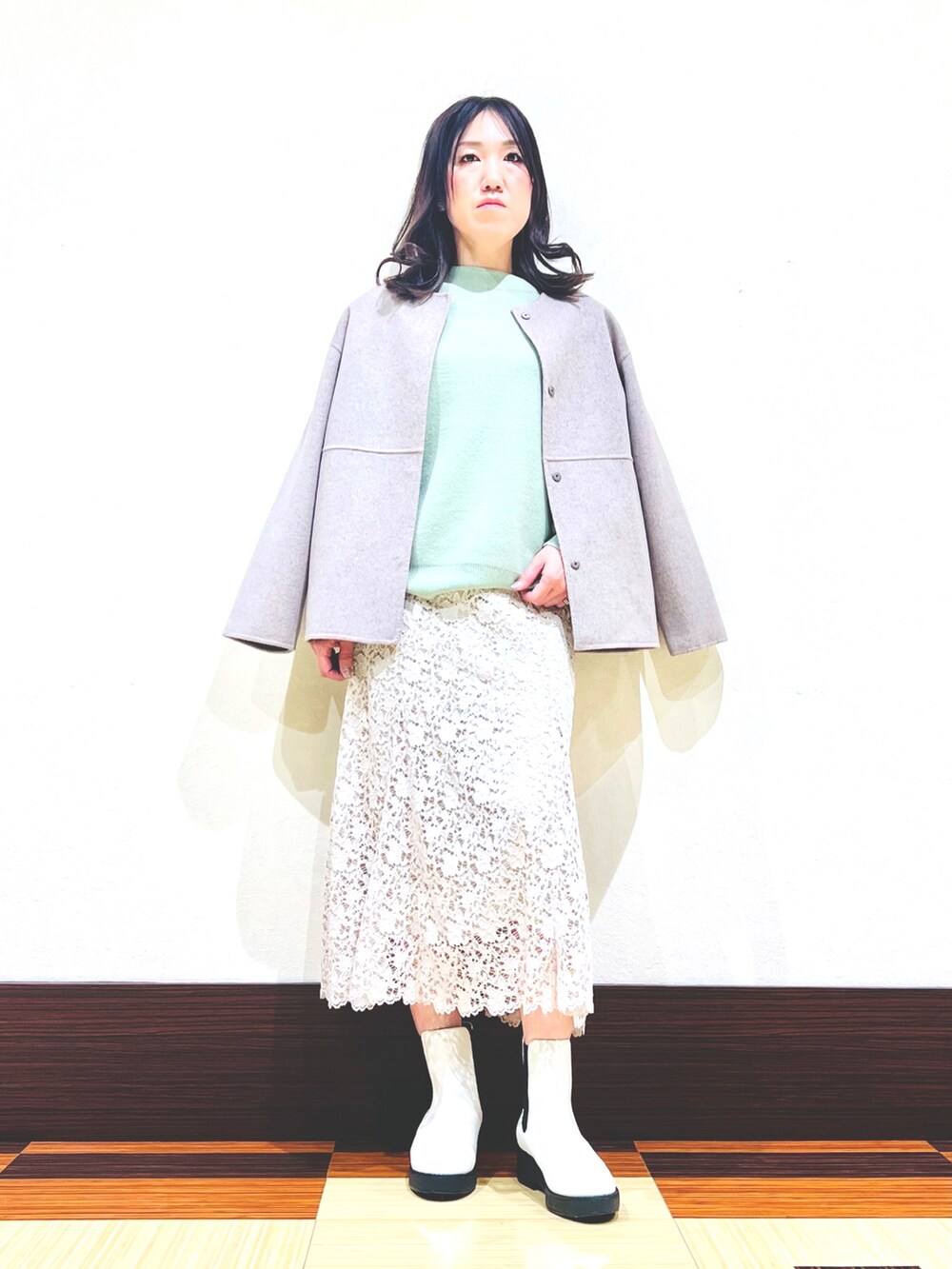 グリーン系のニット/セーター、ホワイト系のブーツ、ベージュ系のスカートを着用したレディースの冬コーディネートの2枚目の写真