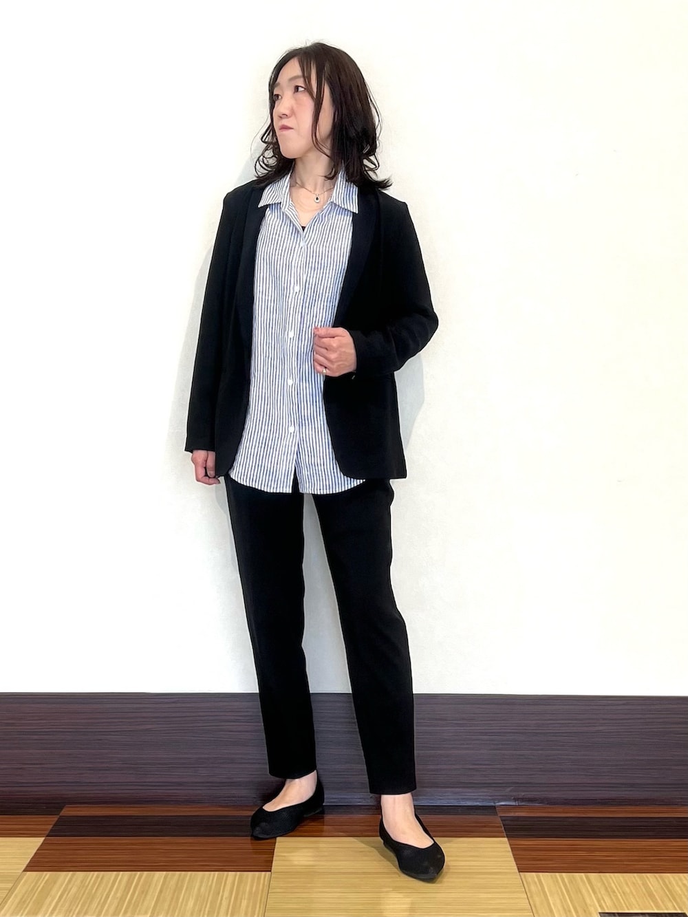 ブラック系のスーツジャケット、ホワイト系のシャツ/ブラウス、ブラック系のスーツパンツを着用したレディースの春コーディネートの3枚目の写真