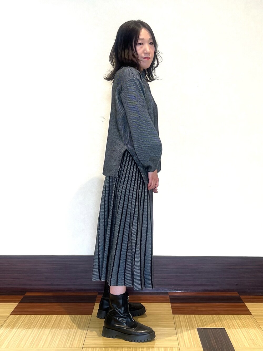 ブラック系のニット/セーター、ブラック系のスカート、ブラック系のブーツを着用したレディースの秋コーディネートの4枚目の写真