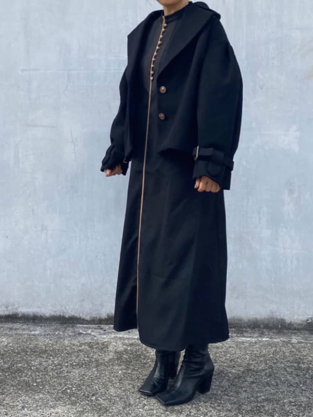 ブラック系のチェスターコート、ブラック系のワンピースを着用したレディースの冬コーディネートの2枚目の写真