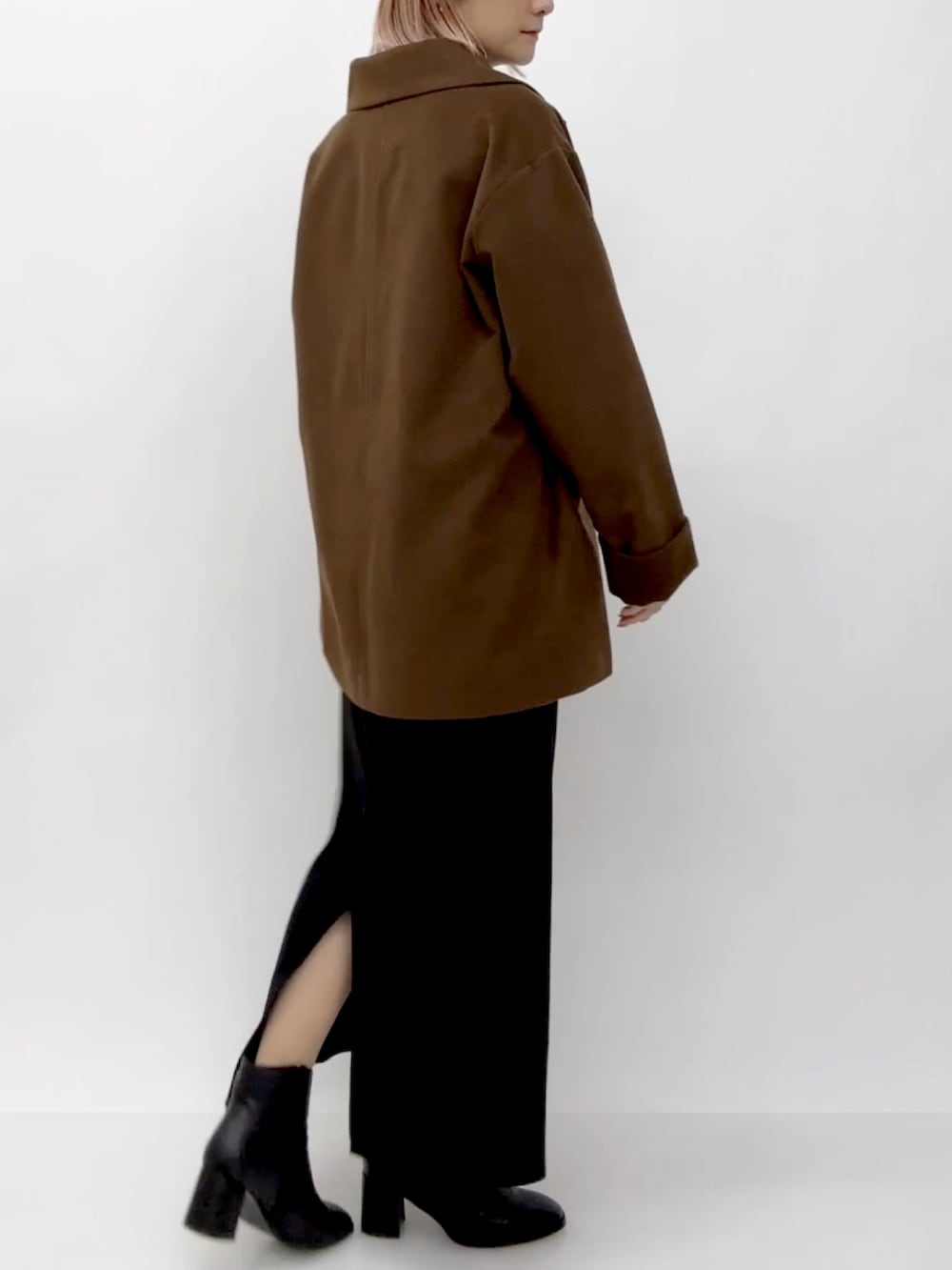 ブラウン系のチェスターコート、ブラック系のスカートを着用したレディースの冬コーディネートの2枚目の写真