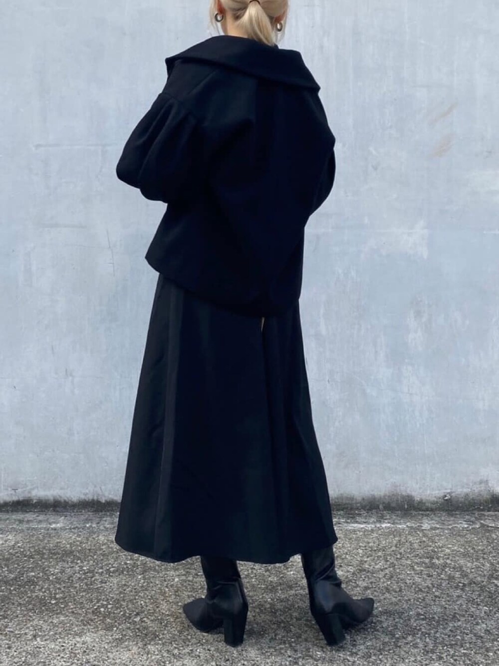 ブラック系のチェスターコート、ブラック系のワンピースを着用したレディースの冬コーディネートの4枚目の写真