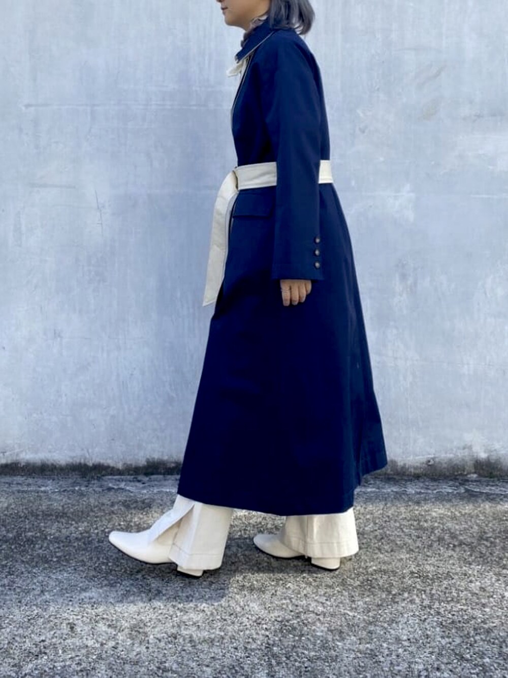 ブルー系のトレンチコート、ホワイト系のデニムパンツ、ホワイト系のブーツを着用したレディースの冬コーディネートの3枚目の写真