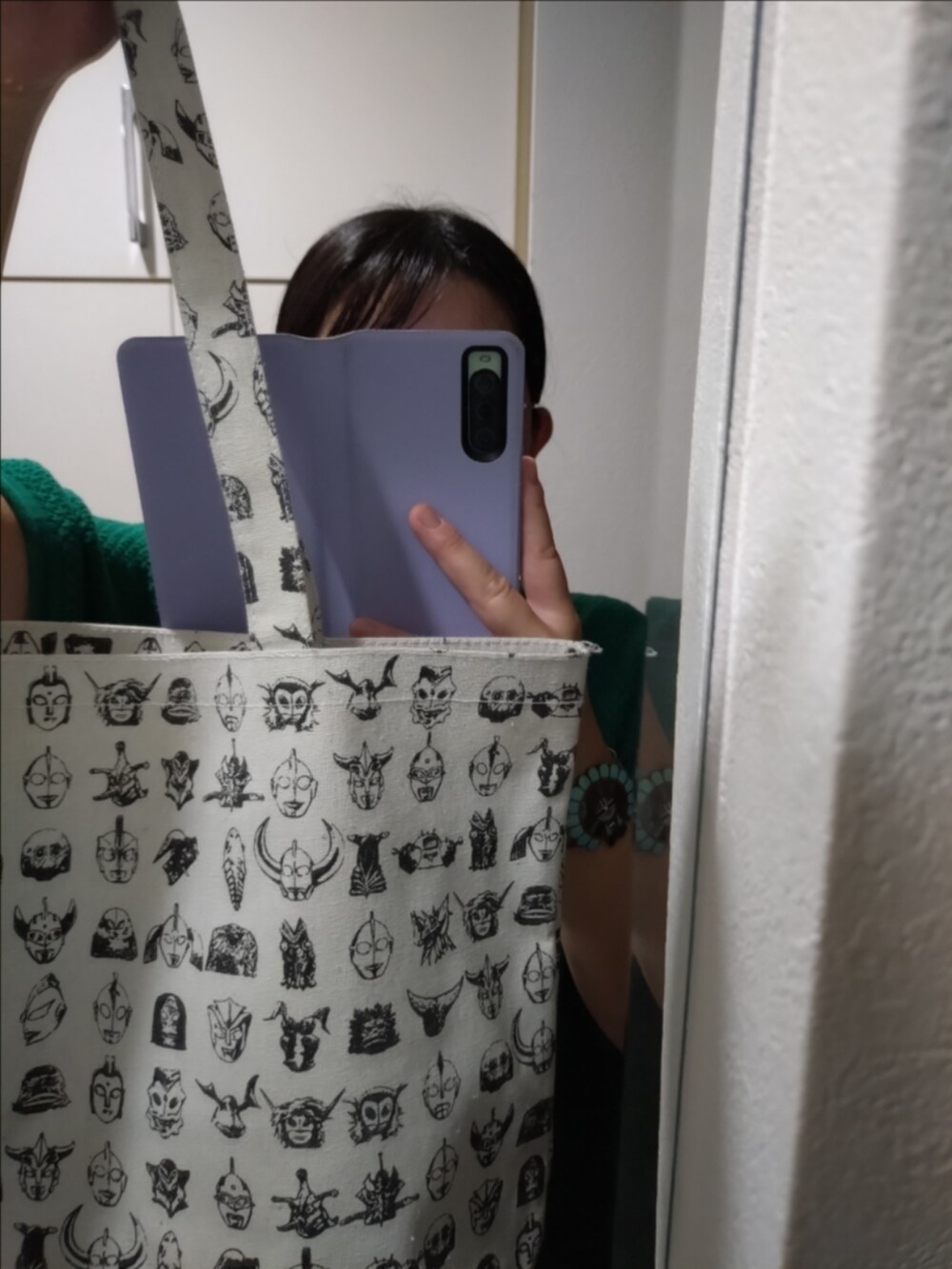 ブルー系のデニムパンツ、ホワイト系のトートバッグ、グリーン系のニット/セーターを着用したレディースの秋コーディネートの2枚目の写真