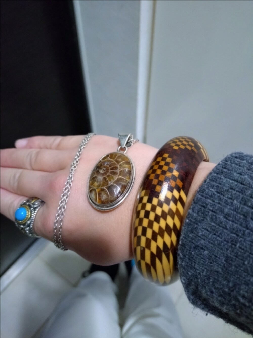 ホワイト系のデニムパンツ、グレー系のニット/セーター、ブラウン系のバングル/リストバンドを着用したレディースの秋コーディネートの2枚目の写真