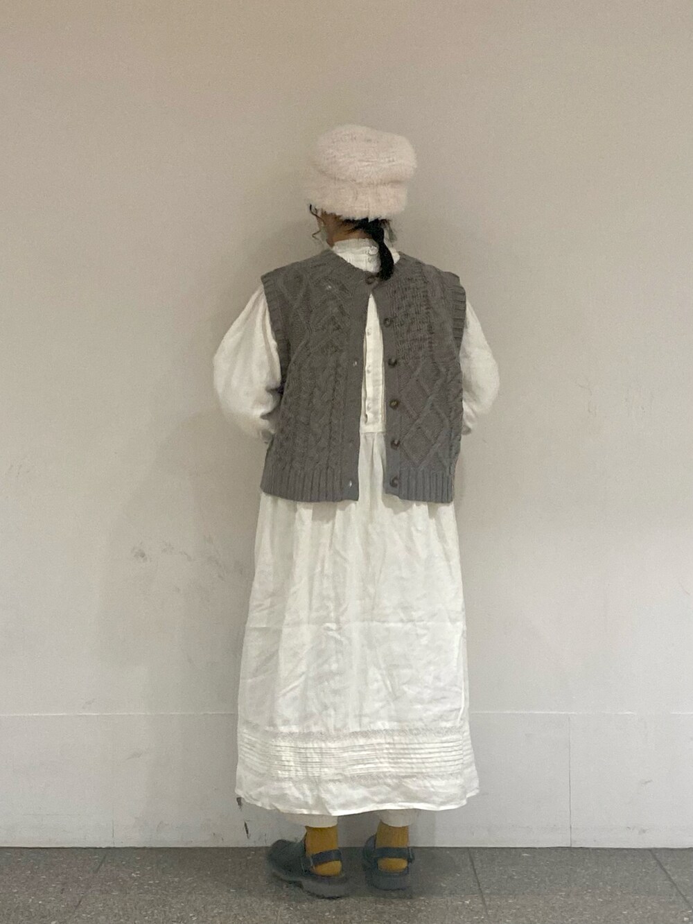 ブラウン系のベスト、ホワイト系のワンピース、ホワイト系のイヤリングを着用したレディースの冬コーディネートの3枚目の写真