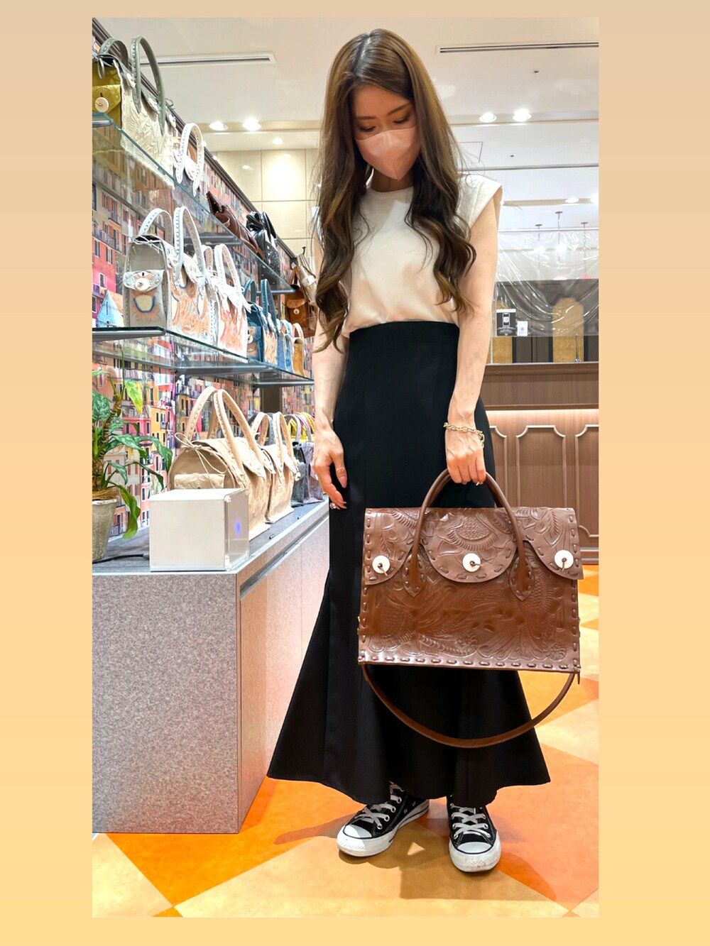 ブラック系のスカート、ブラウン系のトートバッグを着用したレディースの夏コーディネートの2枚目の写真