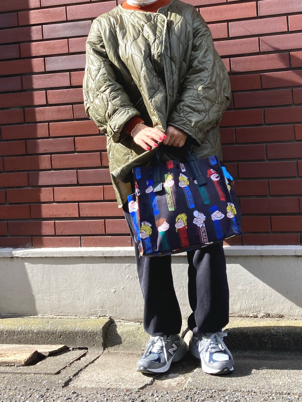 ブラック系のトートバッグ、グレー系のスニーカー、グリーン系のジャケット/アウターを着用したレディースの秋コーディネートの2枚目の写真