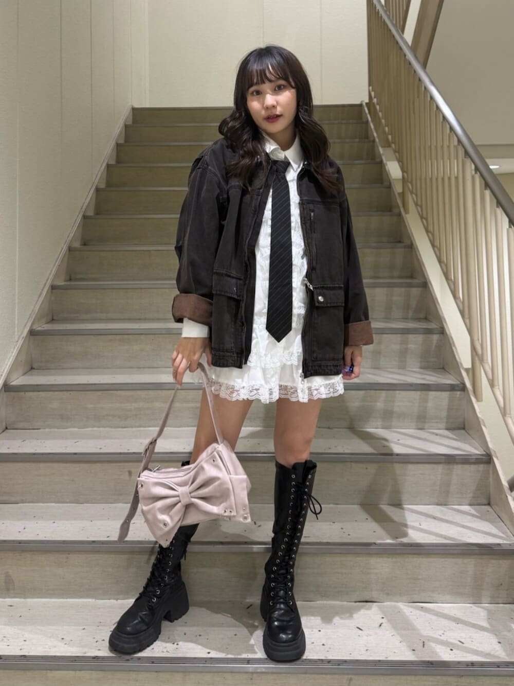 ブラック系のデニムジャケット、ブラック系のブーツ、ホワイト系のシャツ/ブラウスを着用したレディースの秋コーディネートの2枚目の写真