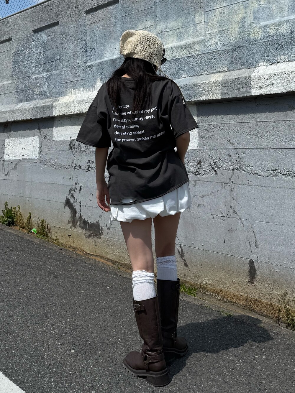 ブラウン系のブーツ、ブラック系のTシャツ/カットソー、ホワイト系のスカートを着用したレディースの春コーディネートの3枚目の写真