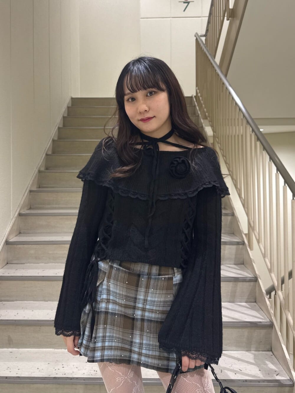 ブラック系のブーツ、ブラウン系のスカート、ブラック系のハンドバッグを着用したレディースの冬コーディネートの6枚目の写真