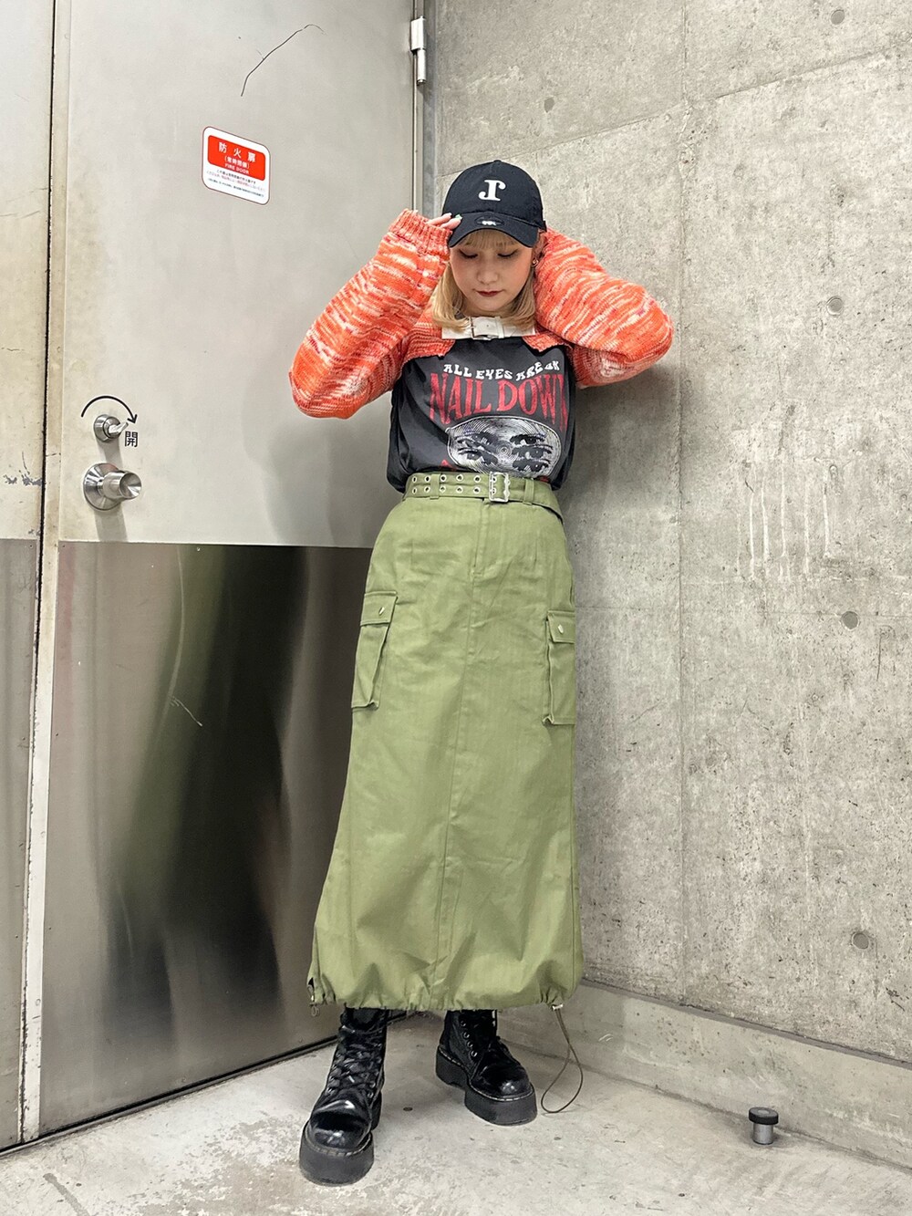 オレンジ系のニット/セーター、ブラック系のTシャツ/カットソー、ベージュ系のスカートを着用したレディースの冬コーディネートの2枚目の写真