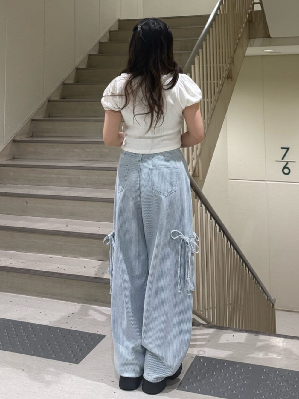 ブラック系のブーツ、ホワイト系のTシャツ/カットソー、ブルー系のデニムパンツを着用したレディースの春コーディネートの4枚目の写真