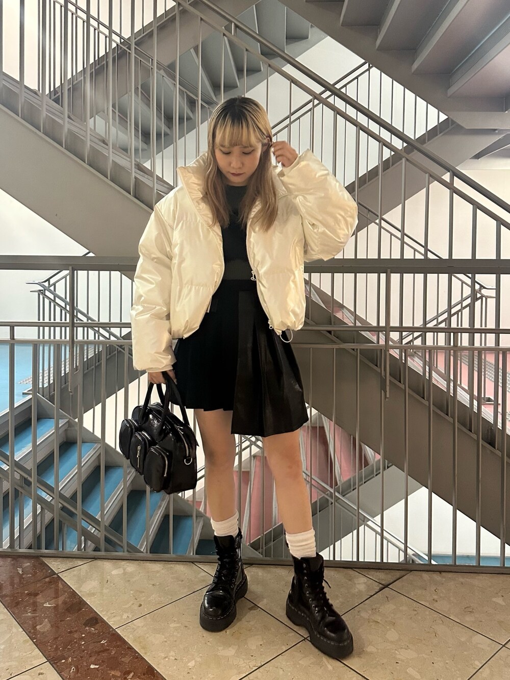 ブラック系のボストンバッグ、ホワイト系のダウンジャケット/コート、グリーン系のニット/セーターを着用したレディースの冬コーディネートの3枚目の写真