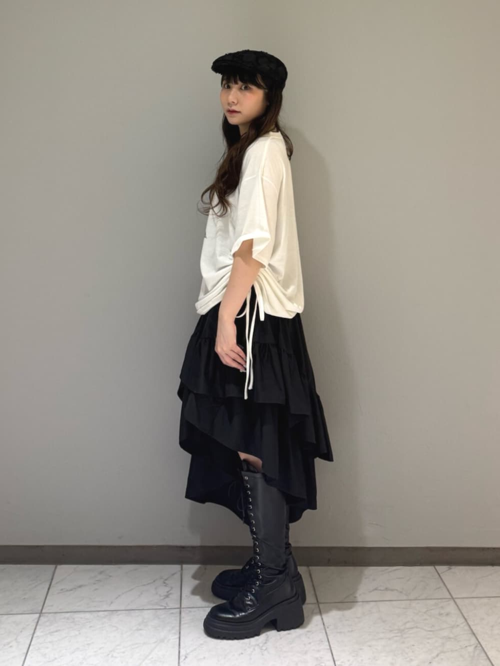 ブラック系のブーツ、ホワイト系のTシャツ/カットソー、ブラック系のスカートを着用したレディースの夏コーディネートの2枚目の写真