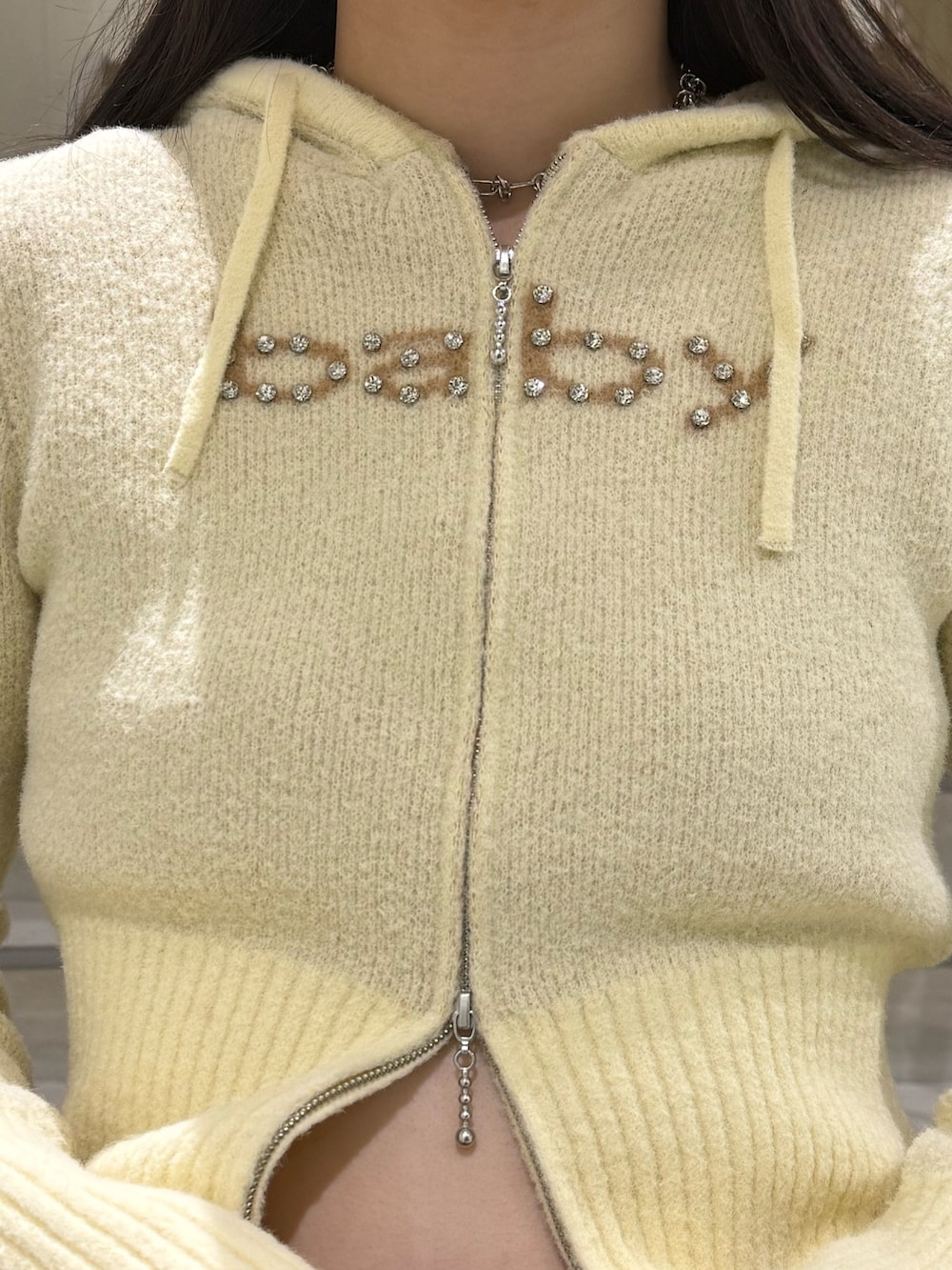 イエロー系のパーカー、ベージュ系のスカート、ブラック系のブーツを着用したレディースの冬コーディネートの8枚目の写真