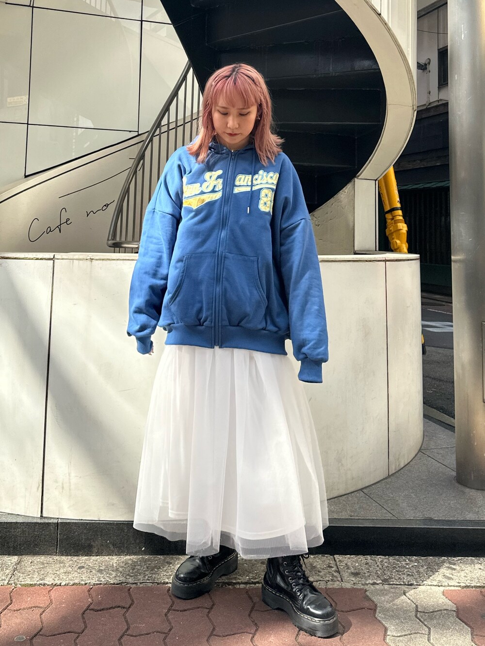 ブルー系のパーカー、ホワイト系のスカート、ブラック系のブーツを着用したレディースの春コーディネートの2枚目の写真