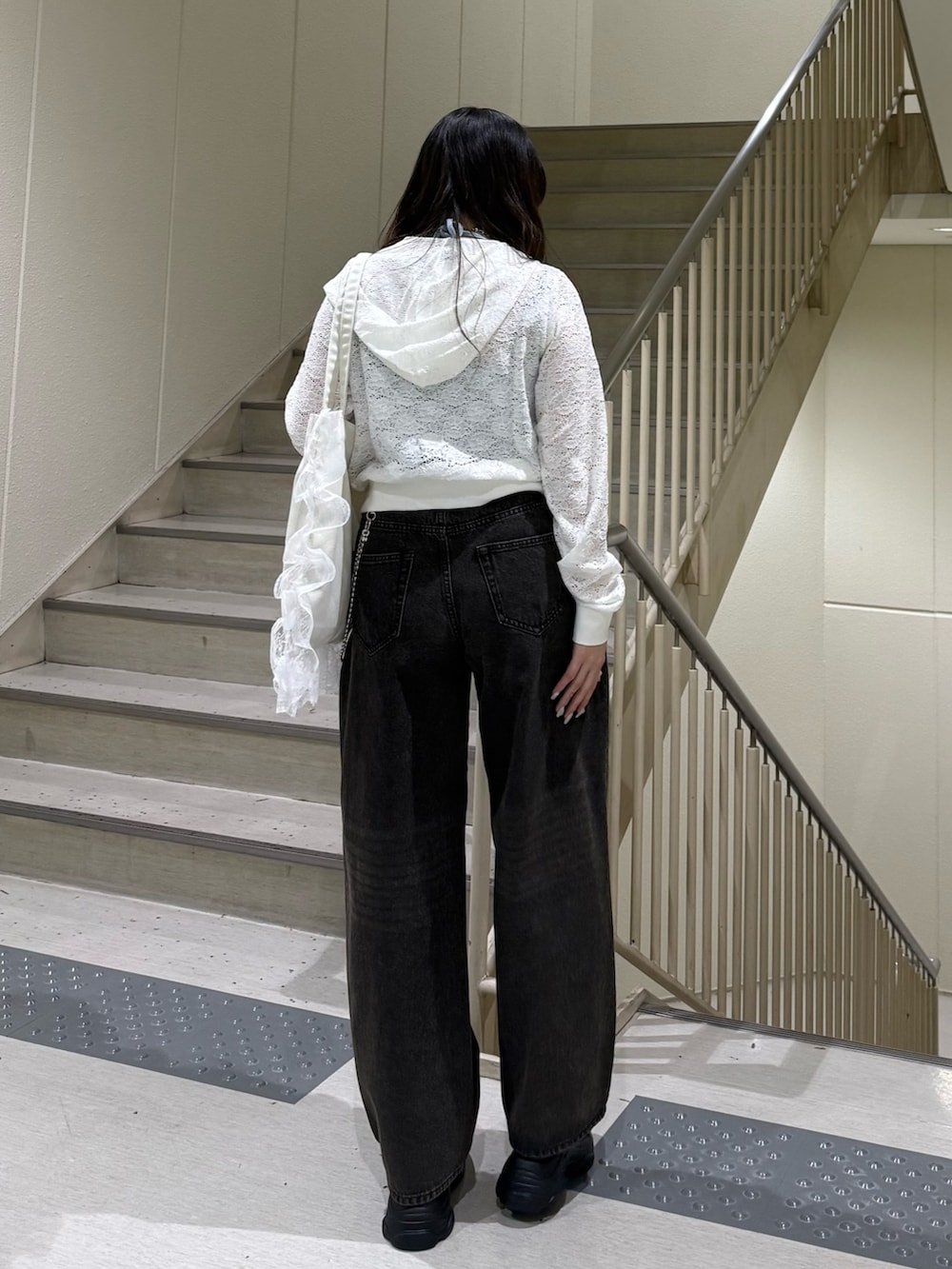 ホワイト系のパーカー、ブラック系のデニムパンツ、ホワイト系のトートバッグを着用したレディースの春コーディネートの4枚目の写真