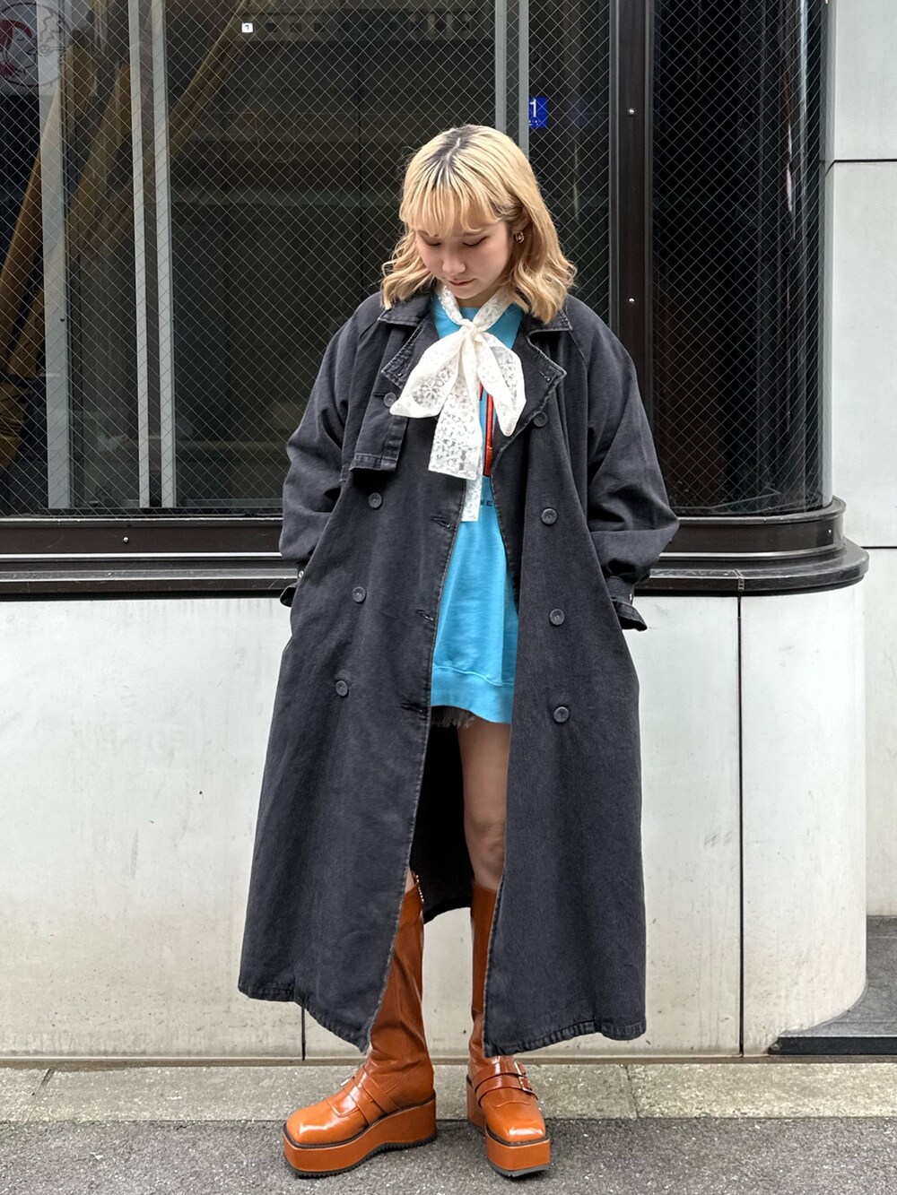 ブラウン系のブーツ、ブラック系のトレンチコート、ブルー系のスウェットを着用したレディースの冬コーディネートの2枚目の写真