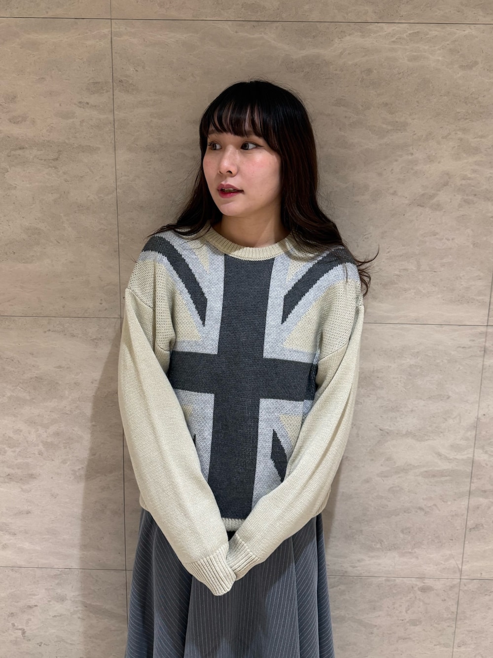 グレー系のスカート、ホワイト系のニット/セーター、ブラック系のブーツを着用したレディースの冬コーディネートの5枚目の写真