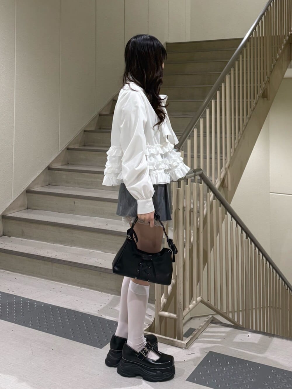 ブラック系のハンドバッグ、ブラック系のローファー、グレー系のスカートを着用したレディースの冬コーディネートの3枚目の写真