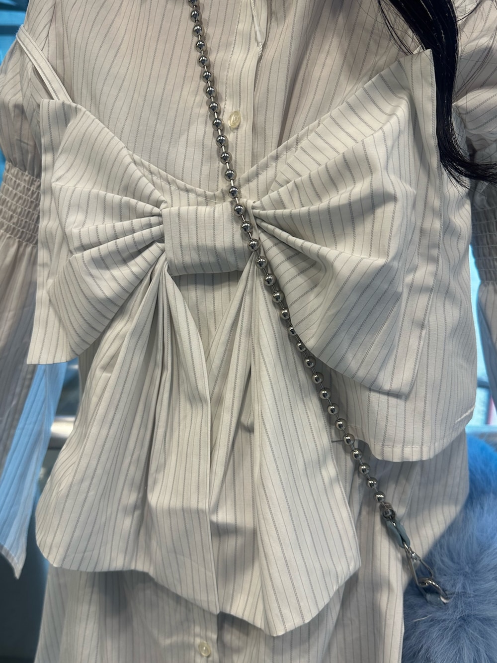 ホワイト系のシャツワンピース、ブルー系のハンドバッグ、ブラック系のブーツを着用したレディースの夏コーディネートの6枚目の写真