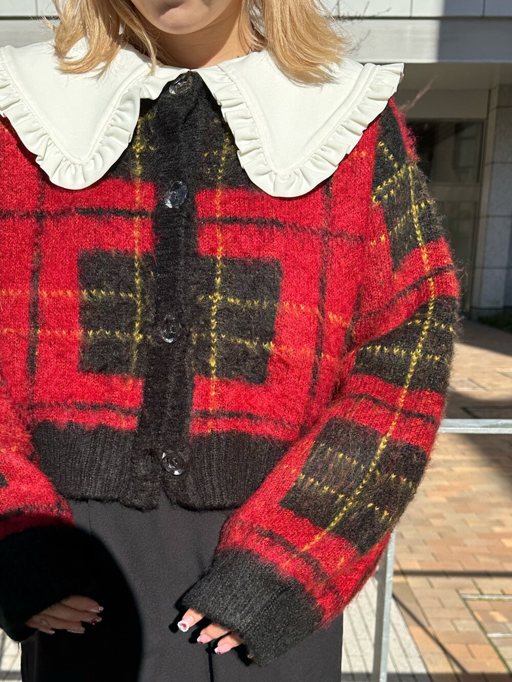 レッド系のカーディガン/ボレロ、ブラック系のワンピース、ブラック系のブーツを着用したレディースの冬コーディネートの5枚目の写真