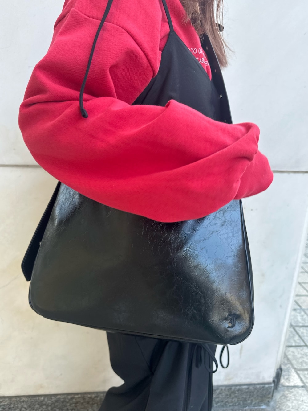 ブラック系のワンピース、ブラック系のショルダーバッグ、レッド系のスウェットを着用したレディースの冬コーディネートの9枚目の写真