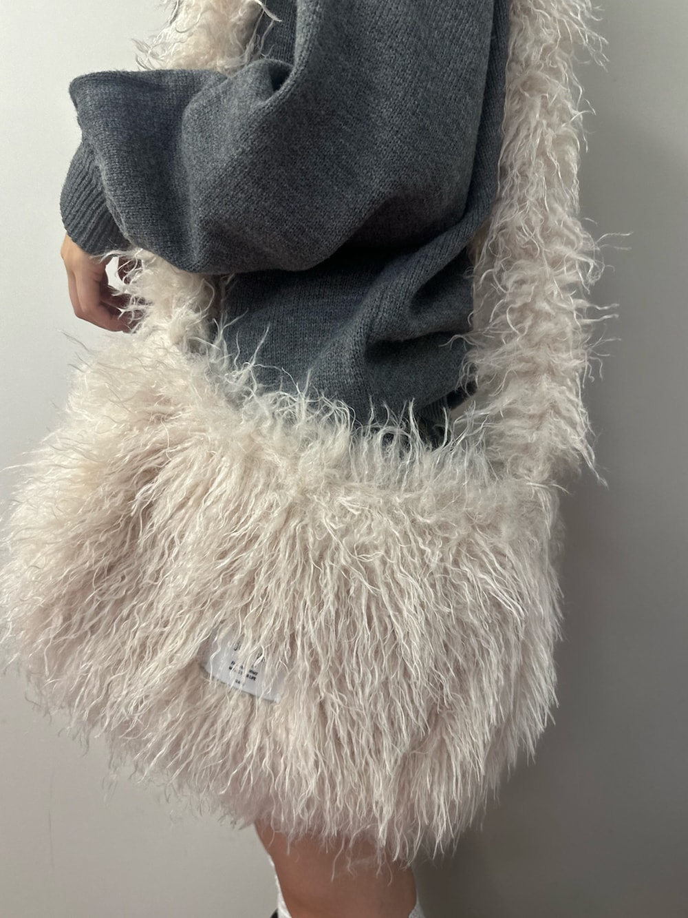 ホワイト系のショルダーバッグ、グレー系のニット/セーター、ブラウン系のその他パンツを着用したレディースの冬コーディネートの8枚目の写真