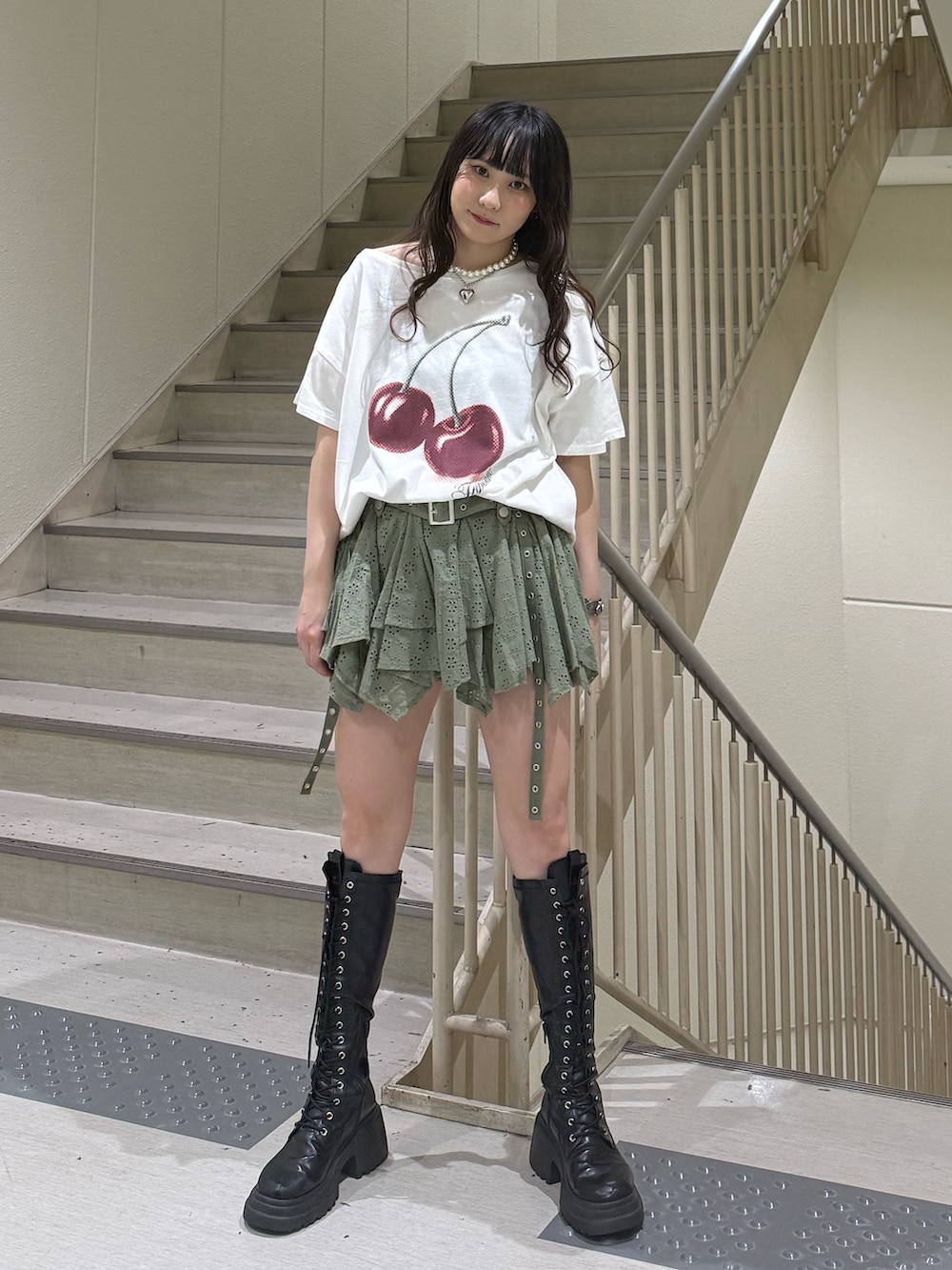 ホワイト系のTシャツ/カットソー、ブラック系のブーツ、グリーン系のスカートを着用したレディースの春コーディネートの2枚目の写真