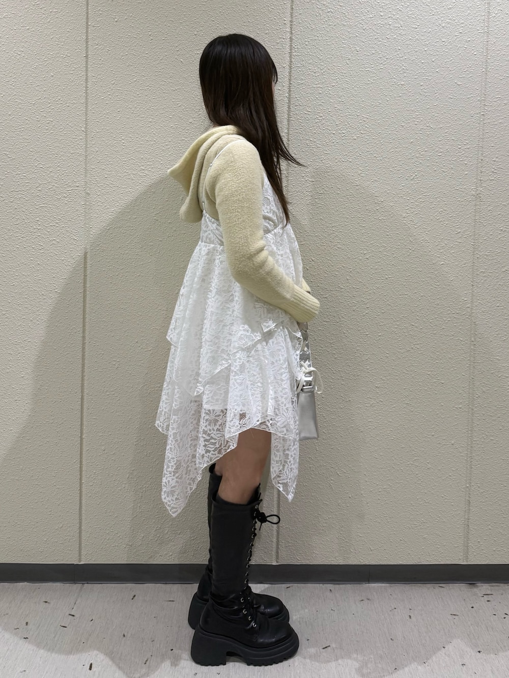 イエロー系のパーカー、ホワイト系のワンピース、シルバー系のハンドバッグを着用したレディースの冬コーディネートの3枚目の写真