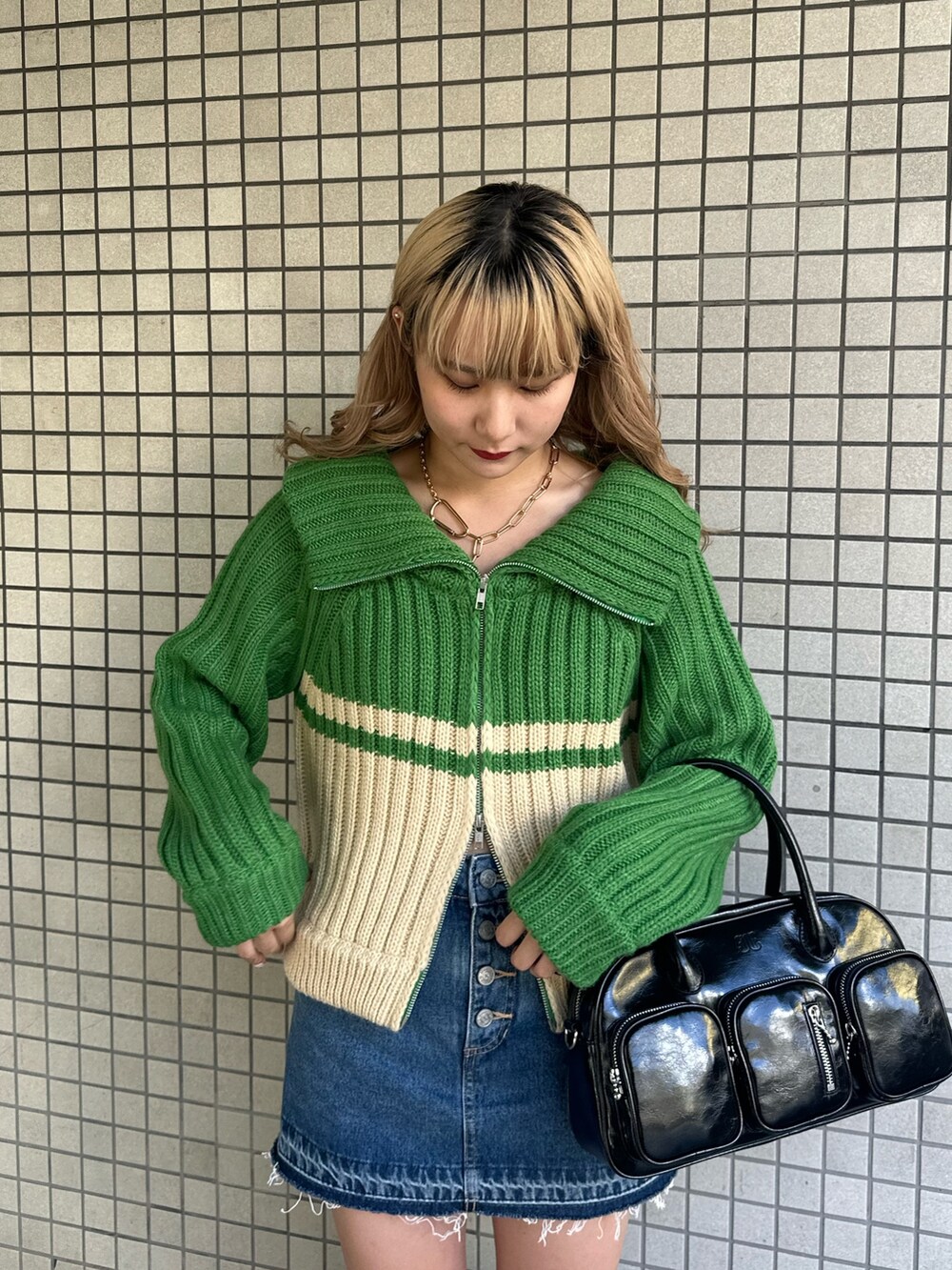 グリーン系のニット/セーター、ブルー系のデニムパンツ、ブラウン系のブーツを着用したレディースの秋コーディネートの4枚目の写真