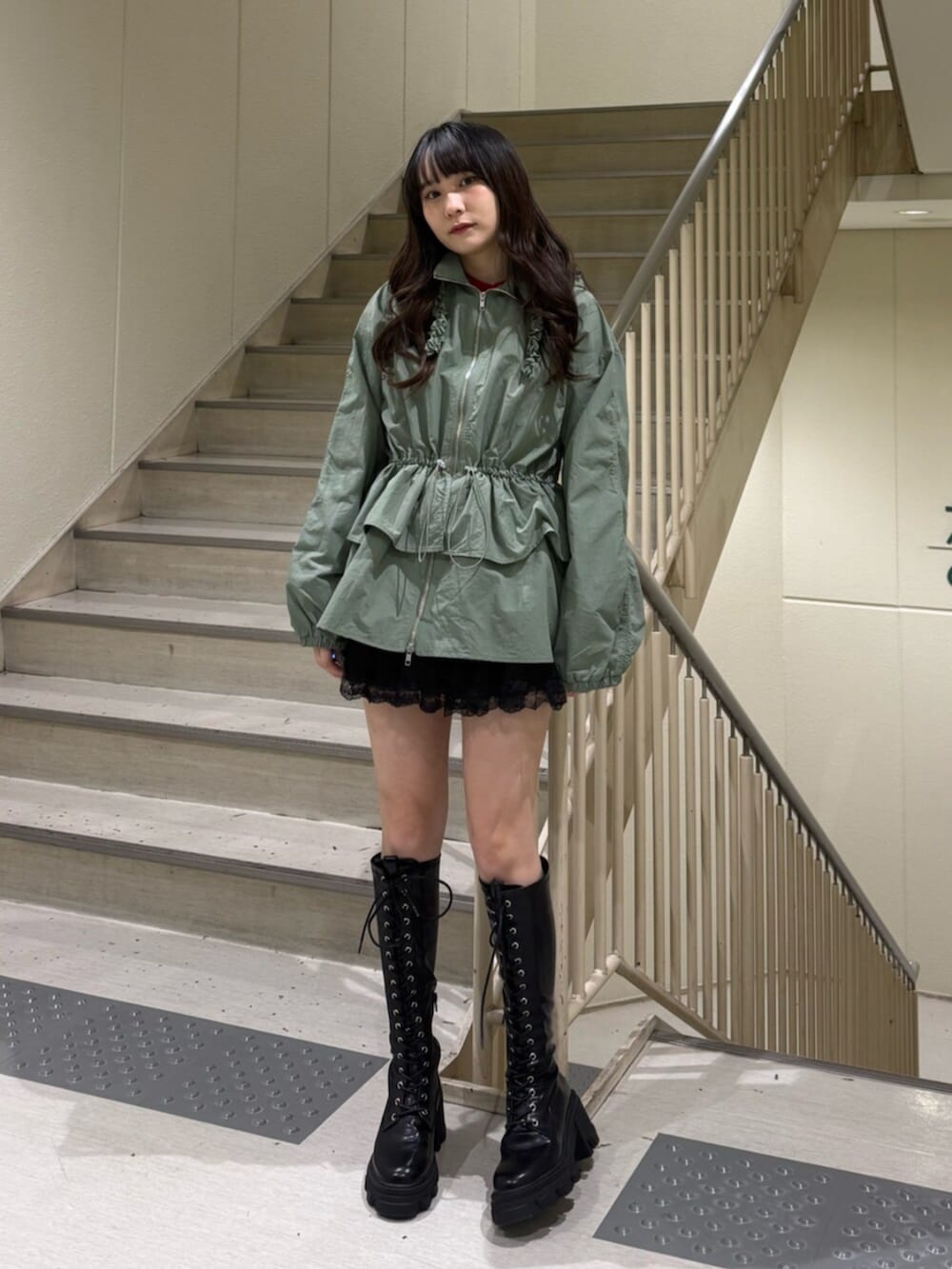 ブラック系のブーツ、グリーン系のナイロンジャケット、ブラック系のその他パンツを着用したレディースの春コーディネートの7枚目の写真