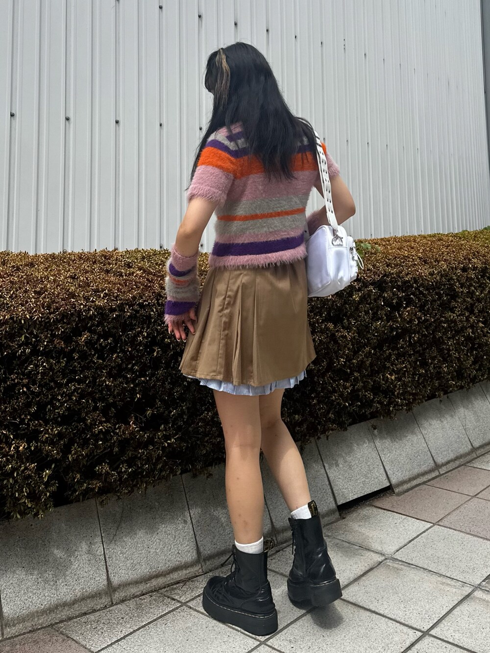 ピンク系のニット/セーター、ベージュ系のスカート、ホワイト系のショルダーバッグを着用したレディースの夏コーディネートの4枚目の写真